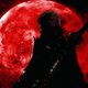 A mysterious silhouette of a person with a sword on their back stands in front of a blood red moon and peers over his shoulder toward the camera.